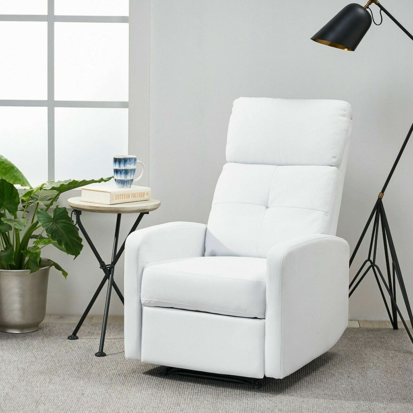 A white recliner chair in front of a plant.
