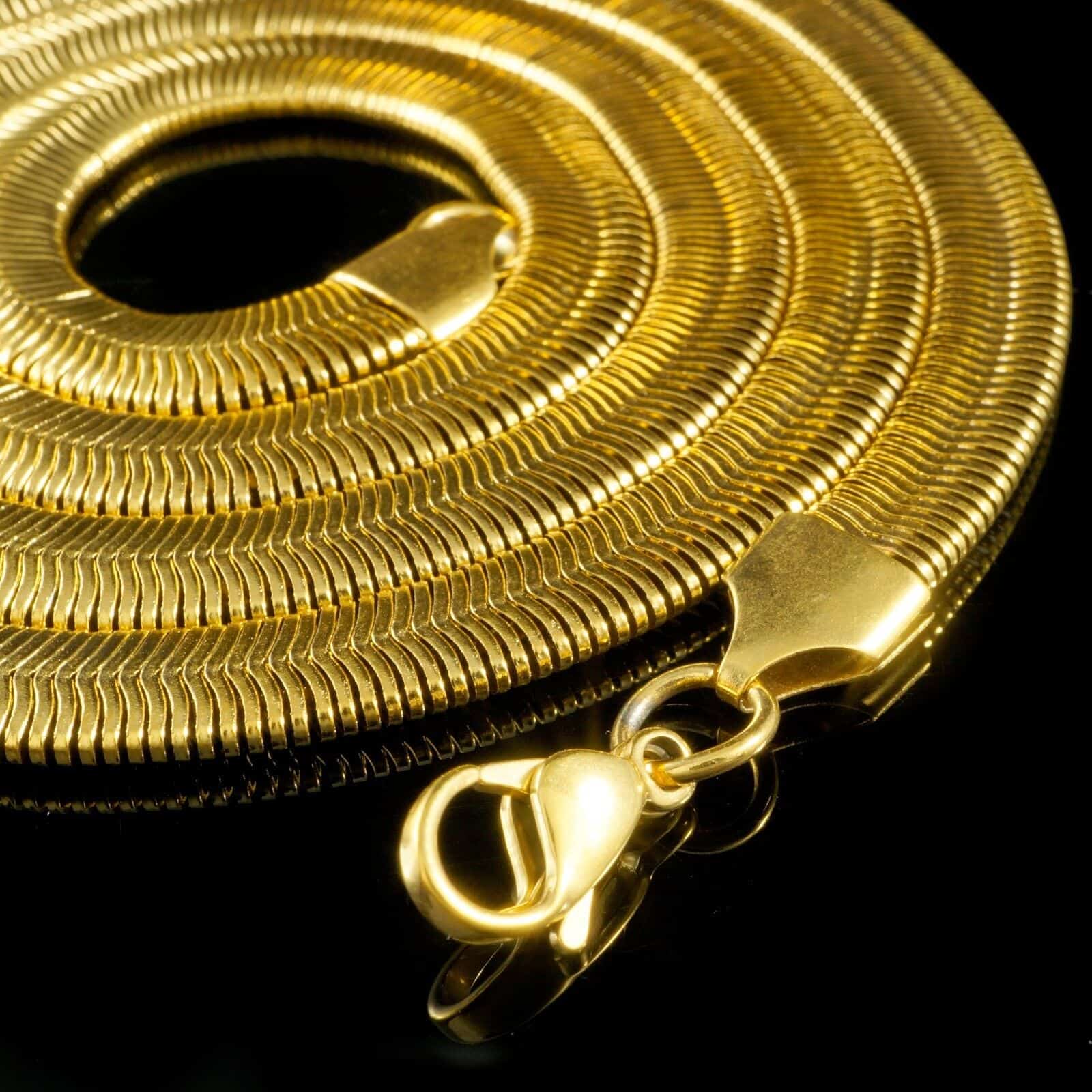 A gold plated snake chain on a black background.