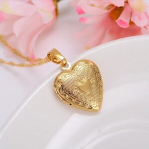 A gold heart locket necklace on a white plate.