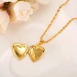 A gold heart locket necklace on a white plate.