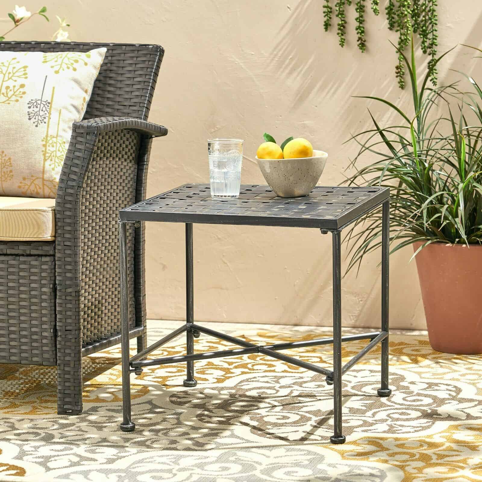 A wicker side table on a patio.