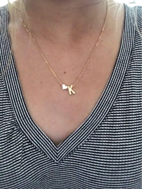 A woman is wearing a necklace with a small heart on it.