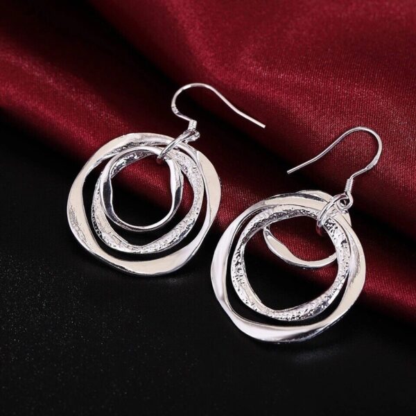 A pair of silver circle earrings on a red background.