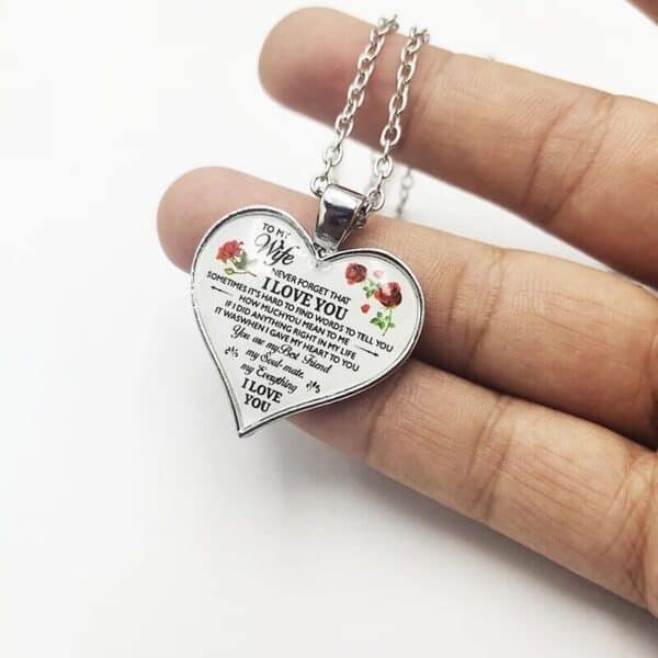 A person holding a heart shaped necklace with a poem on it.