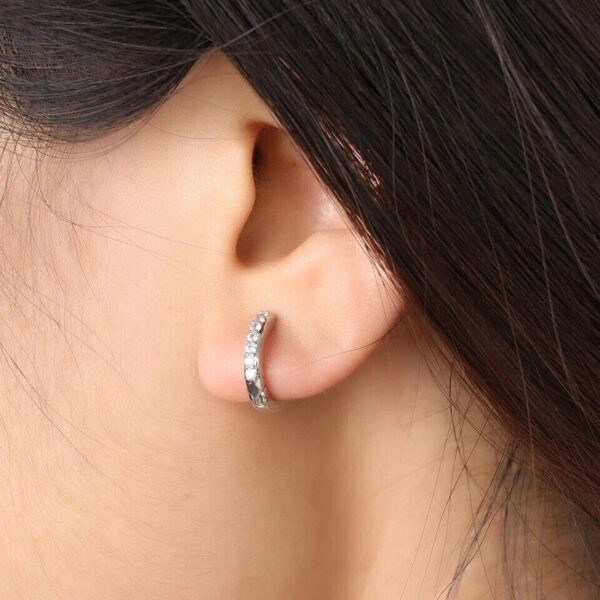 A close up of a woman's ear with a diamond earring.