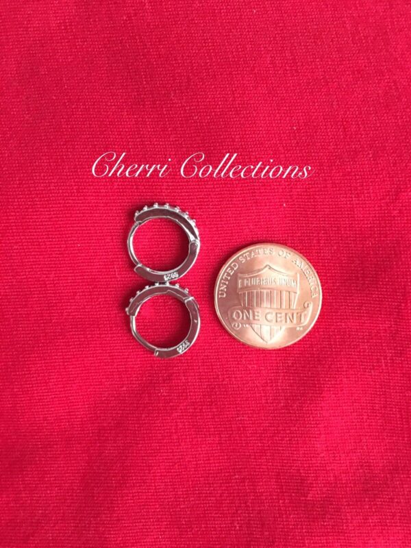 A pair of silver hoop earrings next to a penny.