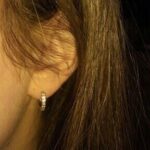 A girl's ear with a pair of hoop earrings.