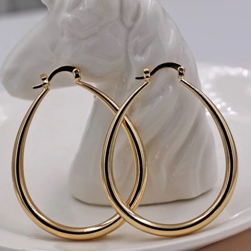 A pair of gold hoop earrings on a white plate.