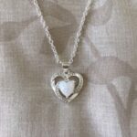 A silver heart necklace with a white opal stone.