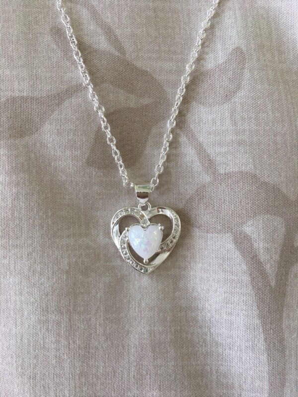 A silver heart necklace with a white opal stone.