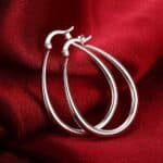 A pair of silver hoop earrings on a red cloth.