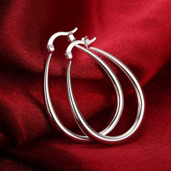 A pair of silver hoop earrings on a red cloth.