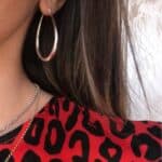 A woman wearing a leopard print shirt and silver hoop earrings.