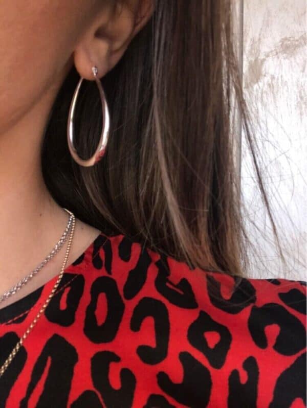 A woman wearing a leopard print shirt and silver hoop earrings.