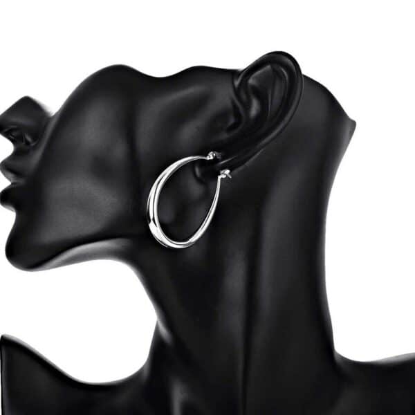 A mannequin wearing a pair of silver hoop earrings.