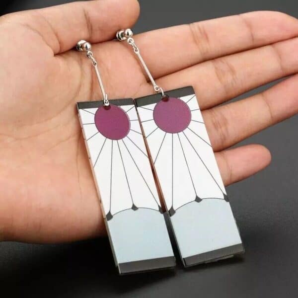 A hand holding a pair of earrings with a purple and white design.