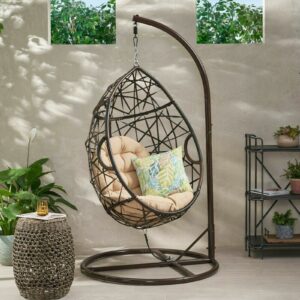 A hanging chair with a potted plant on it.