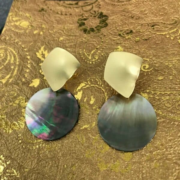 A pair of mother of pearl earrings on a gold background.