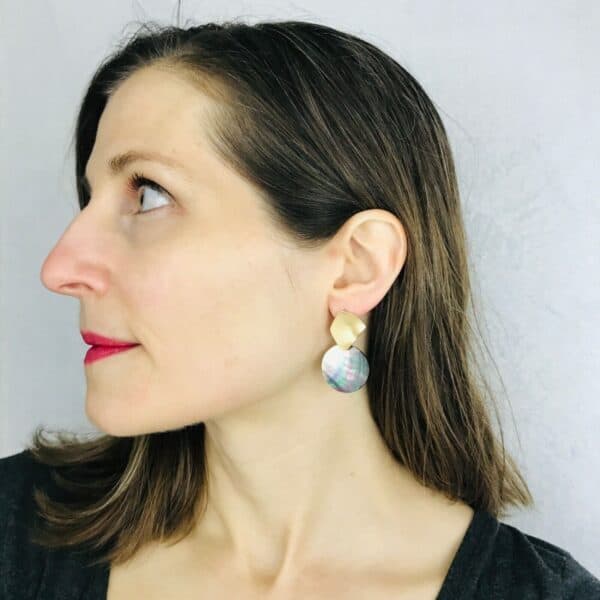 A woman wearing a pair of earrings with a disc in the middle.