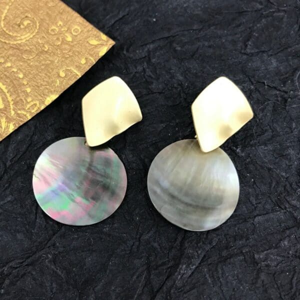 A pair of mother of pearl earrings on a black background.