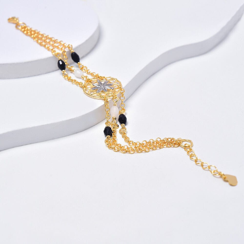 A gold and black beaded bracelet on a white surface.