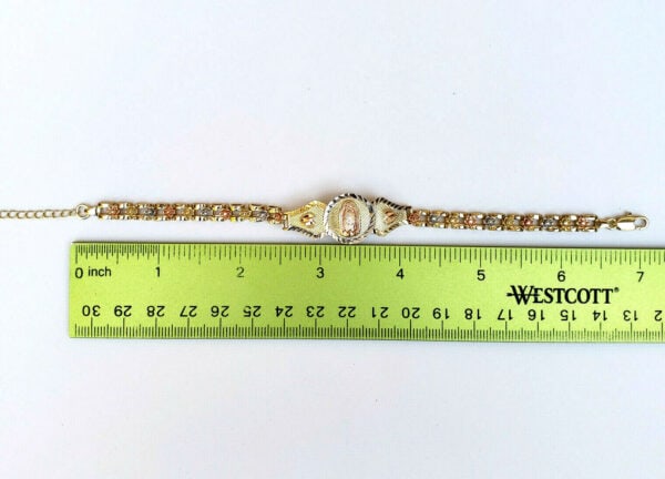 A gold bracelet with a ruler next to it.