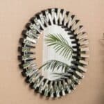 A circular mirror on a wall next to a plant.