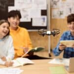 A group of people sitting at a desk with a drone in front of them.