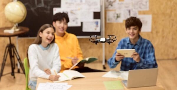 A group of people sitting at a desk with a drone in front of them.