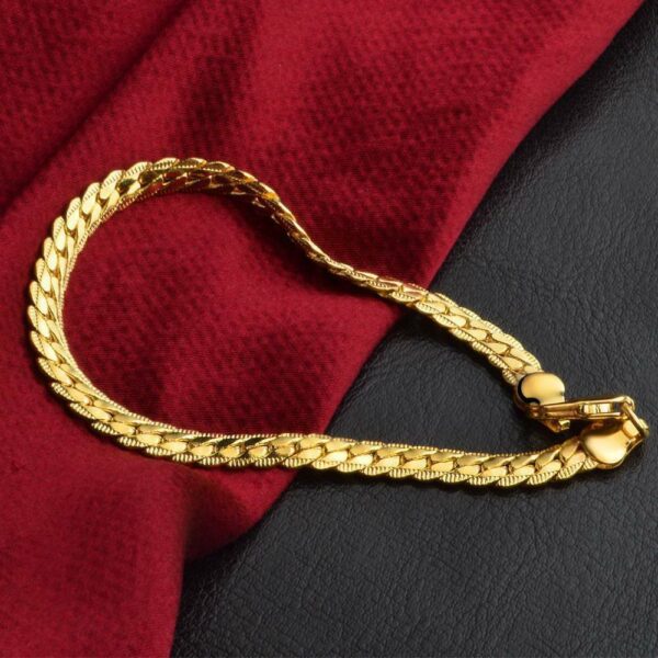 A gold chain bracelet on a red cloth.