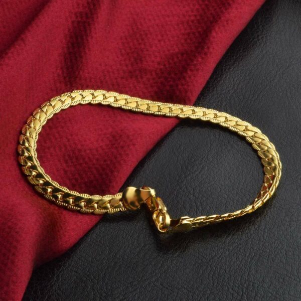 A gold chain bracelet on a red cloth.