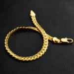 A gold chain bracelet on a black surface.