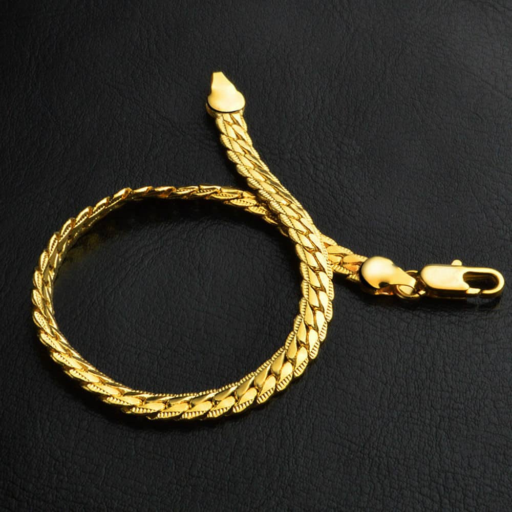 A gold chain bracelet on a black surface.