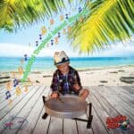 A boy playing a drum on a wooden deck on a beach.