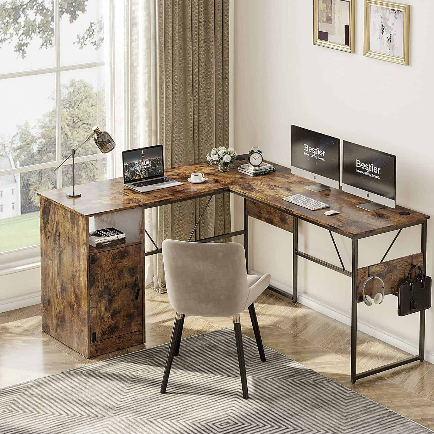 A desk with computers and a chair in front of a window.