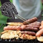 A person is grilling sausages on a grill.