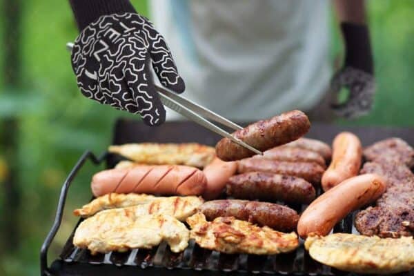 A person is grilling sausages on a grill.