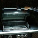 A person putting a light on a grill.