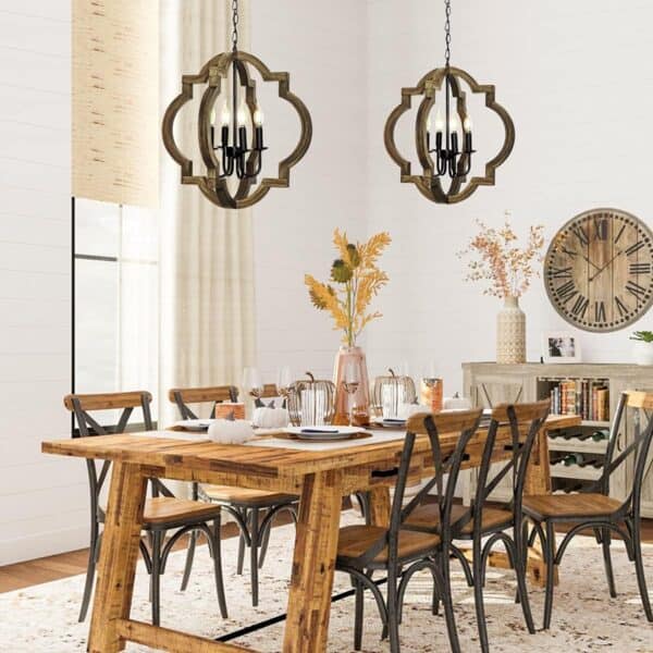 A modern dining room with a wooden table, metal chairs, and two 21.7" Farmhouse orb chandeliers. Light curtains and a large clock on the wall enhance the space.