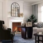 Elegant living room with a lit fireplace, Arched Window Finished Metal Mirror 32×45" Wall Mirror Windowpane Decoration, and modern furniture including black armchairs and a dark coffee table.