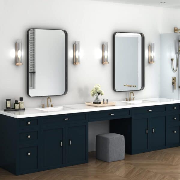 Double vanity bathroom with navy blue cabinets, dual 18 x 28 Inch Rectangle Metal Frame Black Frame Wall Mirrors, and wall-mounted lights. A small plant and toiletries are on the countertop.