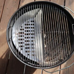 Slow 'N Sear Stainless Steel Charcoal Basket for 18" Charcoal Grills from SnS Grills with an open lid and empty grate on a wooden deck in sunlight.