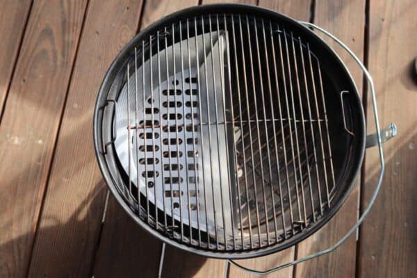 Slow 'N Sear Stainless Steel Charcoal Basket for 18" Charcoal Grills from SnS Grills with an open lid and empty grate on a wooden deck in sunlight.