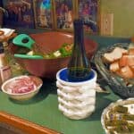 A dinner table with a salad bowl, the Mini Ice Cube Maker Pink Silicone Bucket Ice Mold and Storage Bin, sliced bread, red onions, and condiments.