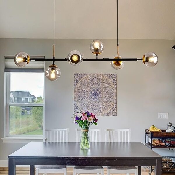 Modern dining room with a black table and white chairs under a Mid-Century Light Pendant Lighting Mid-Century Glass Globes Chandelier Black, featuring a wall tapestry and a vase of flowers.